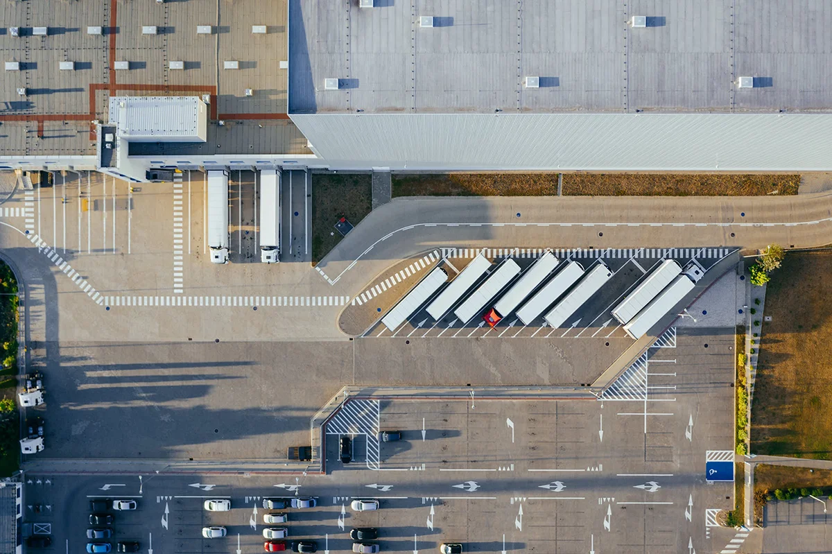  logistics center viewed from above with trucks trailers and cars near streets and a warehouse